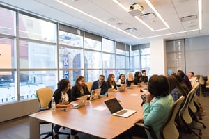 a meeting room with many people on laptops talking