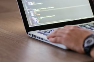a close up of a hand working on a laptop with code