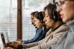 a close-up of four people with headsets on there computers in a room