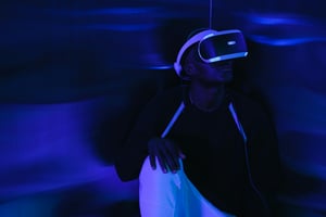 a dark room with little soft blue light that illuminates parts of a persons face